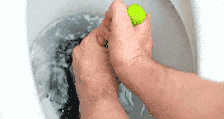 man pushing a plunger into a toilet with two hands.