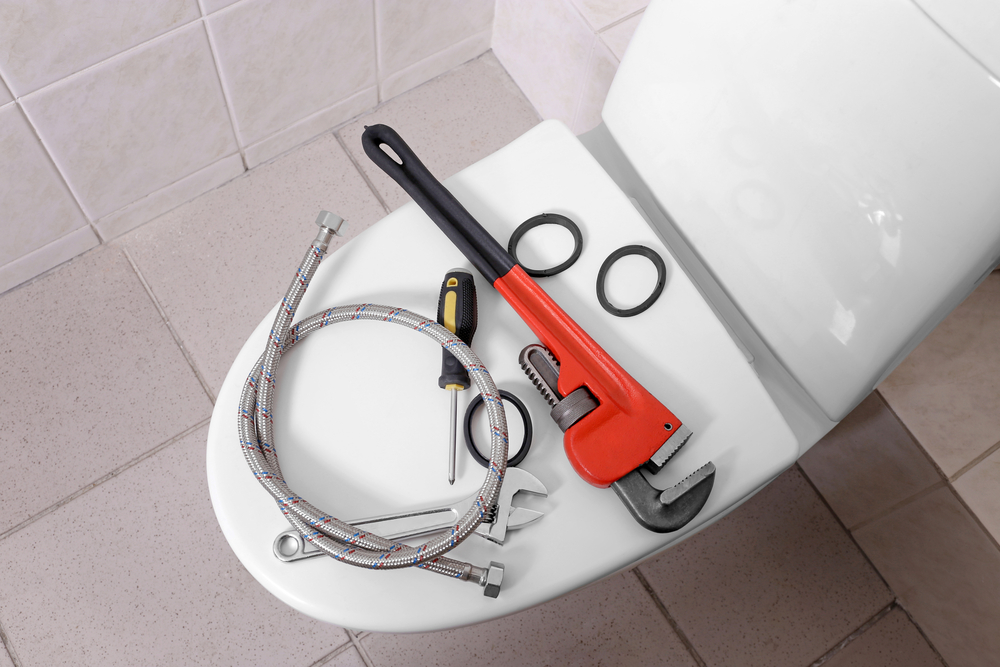 tools sitting on top of the lid to a toilet